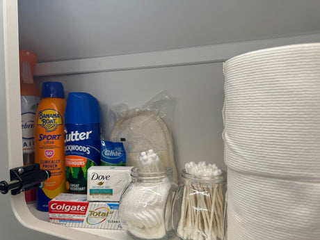 A well-stocked shelf in an RV rental, featuring essential toiletries: sunscreen, bug spray, soap