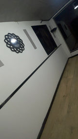 Stylish RV rental interior: white wall, black decorative mirror, dark trim, and light wood floor visible in an angled view.
