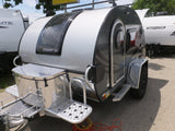 Compact silver and black teardrop RV for rental, equipped for outdoor travel. Ideal for camping adventures.