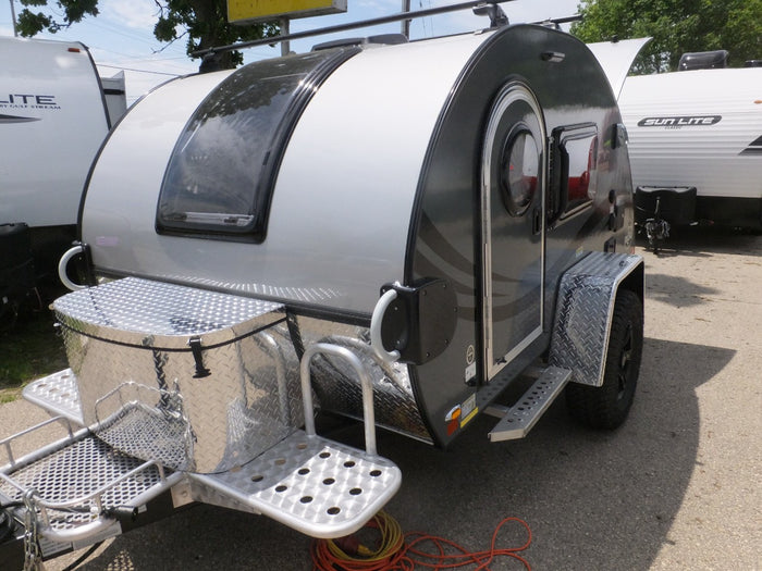 Compact silver and black teardrop RV for rental, equipped for outdoor travel. Ideal for camping adventures.