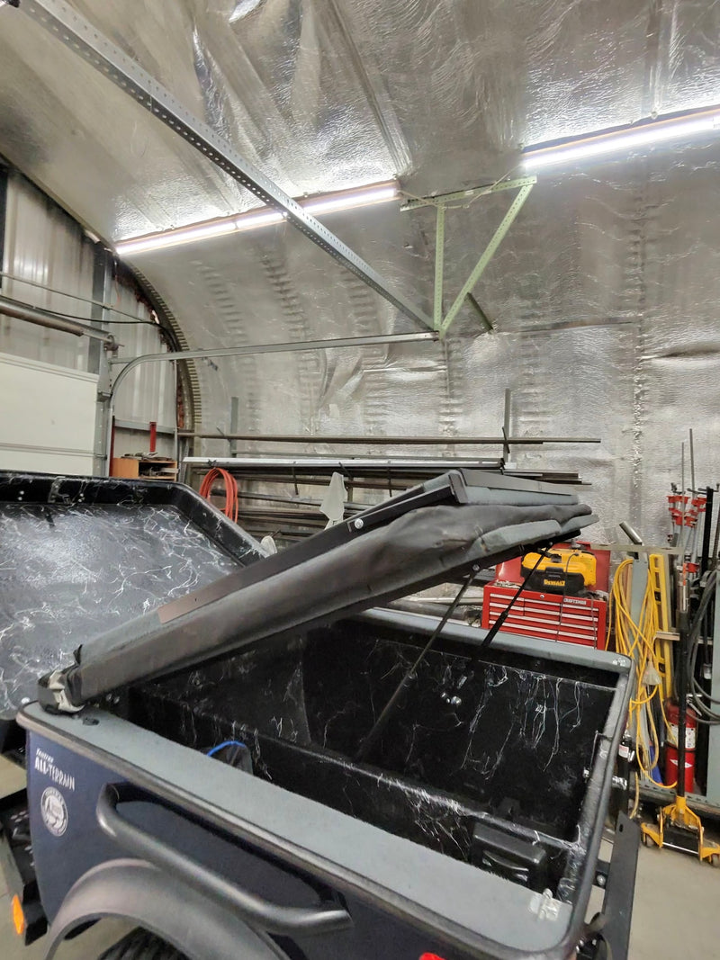 Open Tentrax trailer bed, possibly for an RV rental, showing a unique black interior with white streaked pattern, inside a garage. — photo 8
