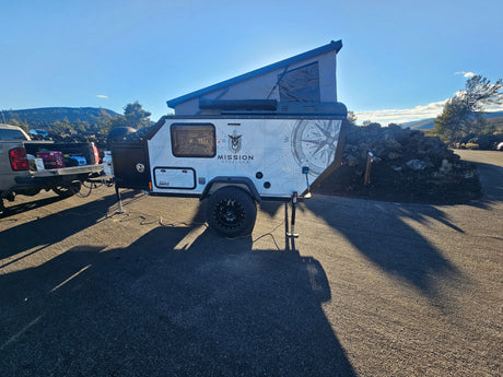 RV rental: Mission Overland pop-up trailer, hitched to a truck, set up for outdoor camping with long shadows.