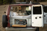 Inside this custom camper van, ideal for RV rental, a bed, kitchen, and pull-out stove are visible.