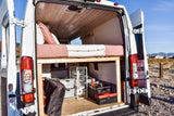 Rear view of an RV rental camper van, revealing a comfy bed platform over ample storage with bins & tools. Ready for trips!