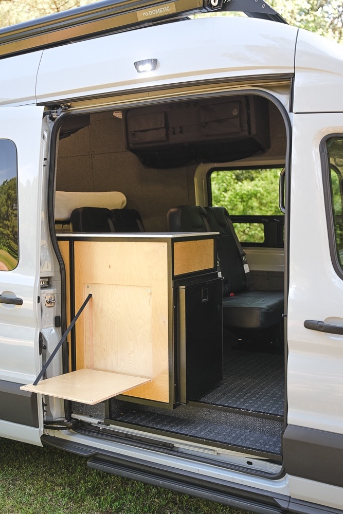  a custom wooden counter with a fold-down table and fridge optimizes space for travel.|Relaxing on an RV rental with legs propped up — photo 3