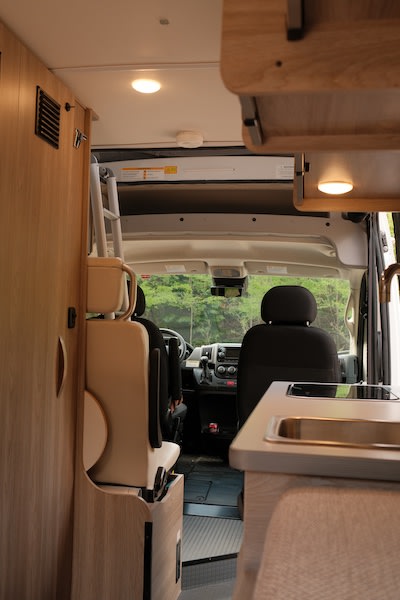  light wood RV rental overhead cabinet displaying organized beige dishes and dark cookware — photo 19