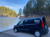 A dark blue Ram ProMaster City camper van on a misty lake boat ramp, perfect for your next RV rental adventure.