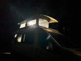 Night helicopter flight: Underslung equipment illuminated, a unique journey contrasting with an RV rental experience.