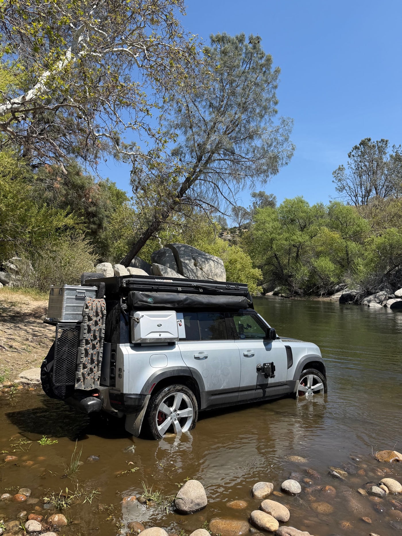 Overlanding-ready Land Rover Defender wading in a river, a rugged adventure setup far from a typical rv rental experience. — photo 3
