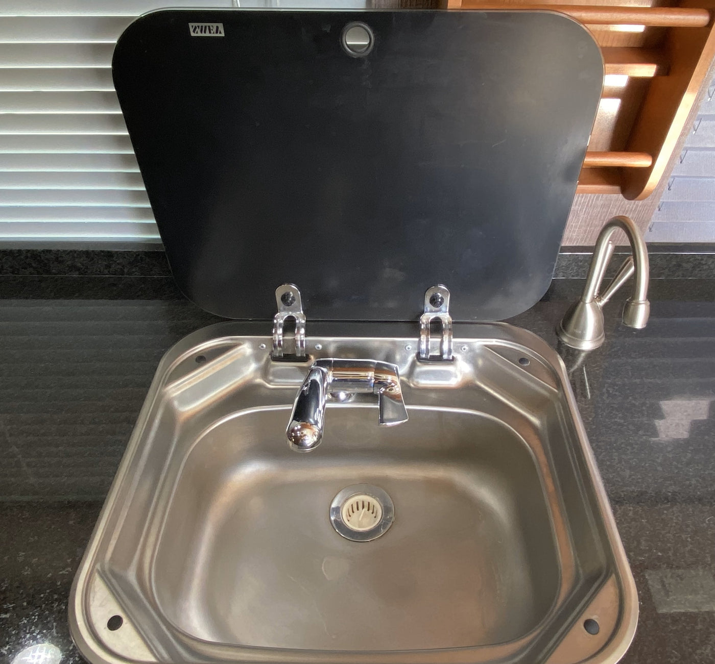  and corner sink for travelers|RV rental compact kitchen sink with chrome faucet and black folding cover.|A Frigidaire Gallery induction|Inside an RV rental compact refrigerator. Features include a top freezer compartment|Cozy rv rental bed with white linens and pillows — photo 10