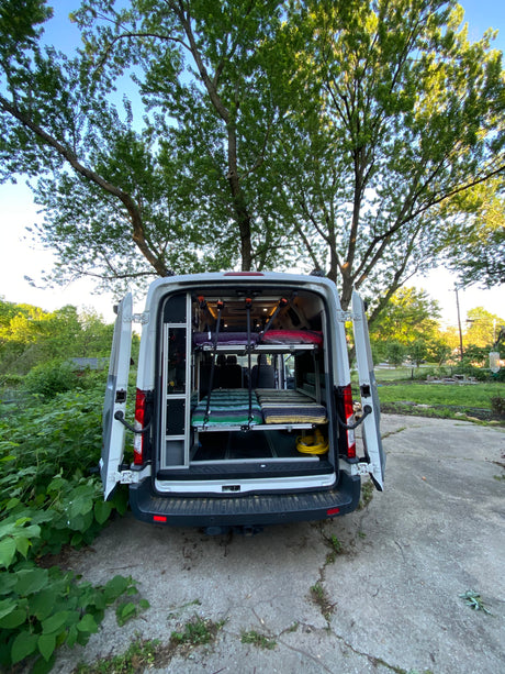 RV rental van's rear view, revealing a custom interior with two levels of bunk beds. Ideal for group camping.