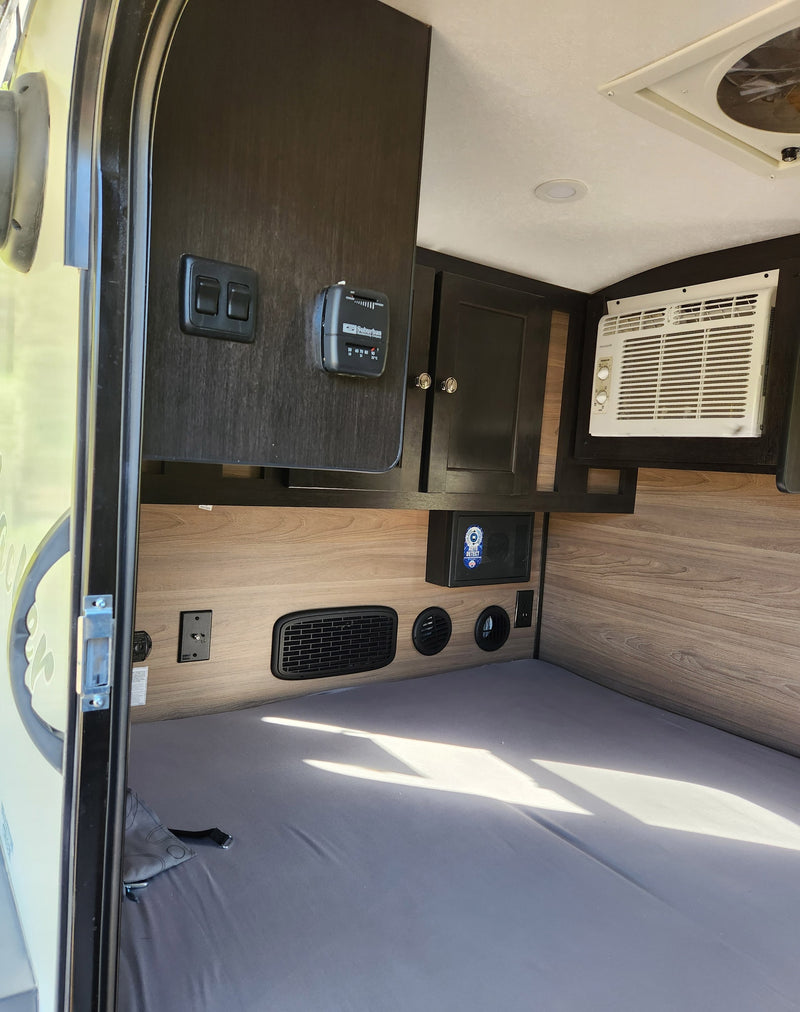 RV rental interior view: compact sleeping area with an AC unit, thermostat, and storage cabinetry clearly visible. — photo 6