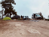 Group adventure at a misty mountain campsite with an RV rental, SUV, and tent. Friends gathered enjoying the wilderness.