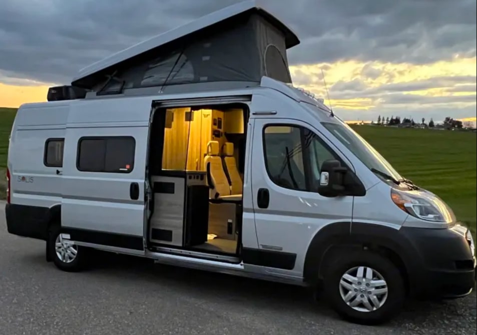 Explore with this modern rv rental: a silver camper van with an extended pop-top and illuminated interior