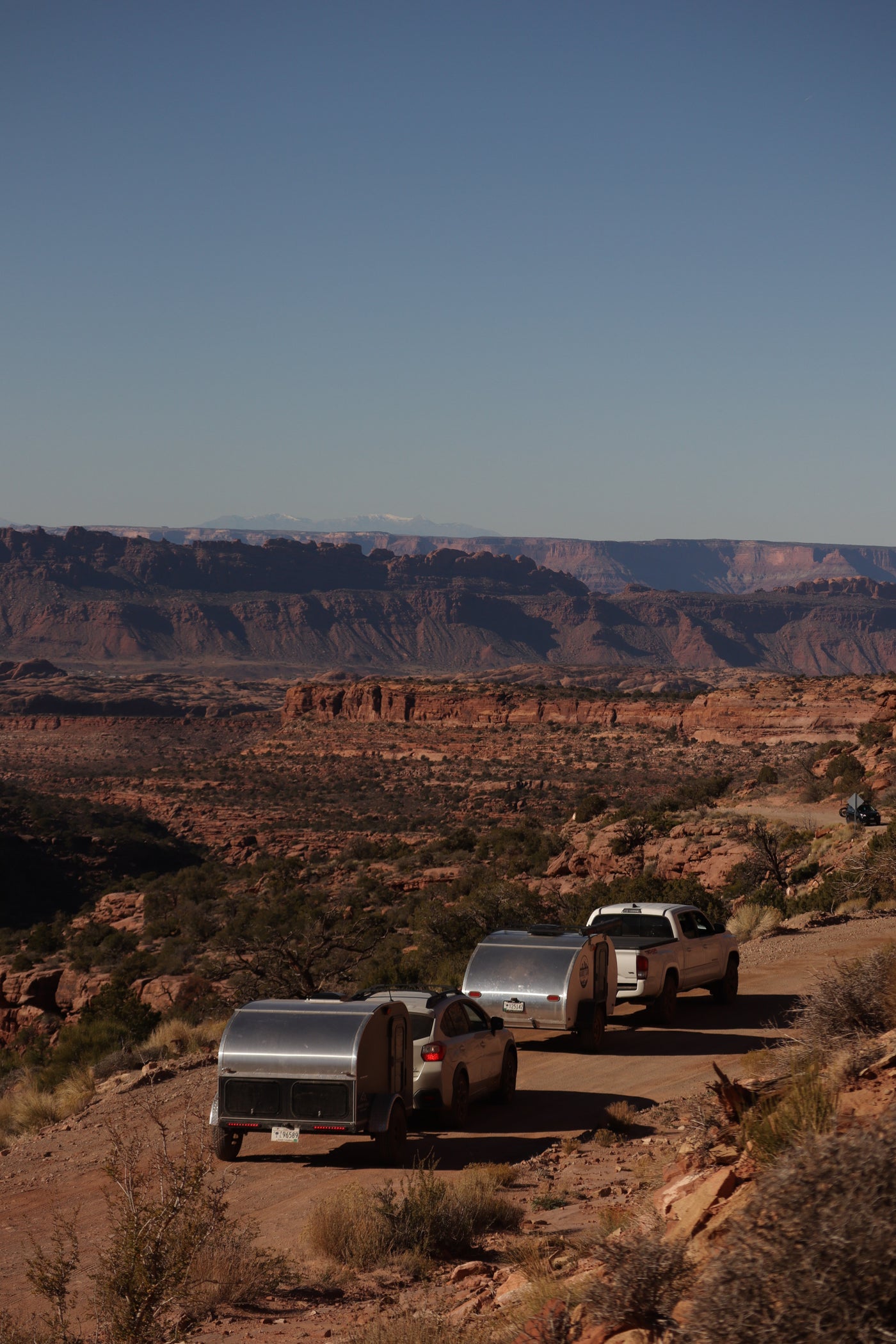 Teardrop RV rentals navigate a rugged dirt road through a vast desert canyon, ideal for off-grid camping adventures. — photo 20