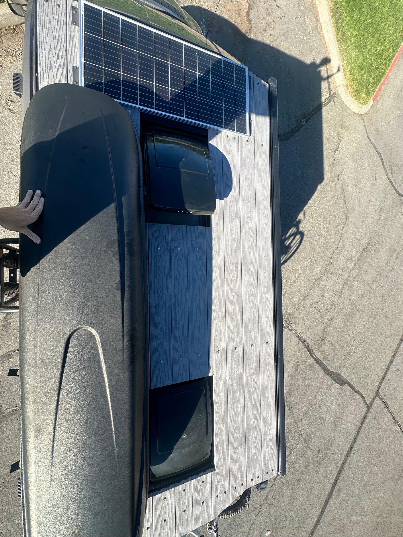 This RV rental roof shows a solar panel, black cargo box, and two vents on textured decking. Ready for travel!