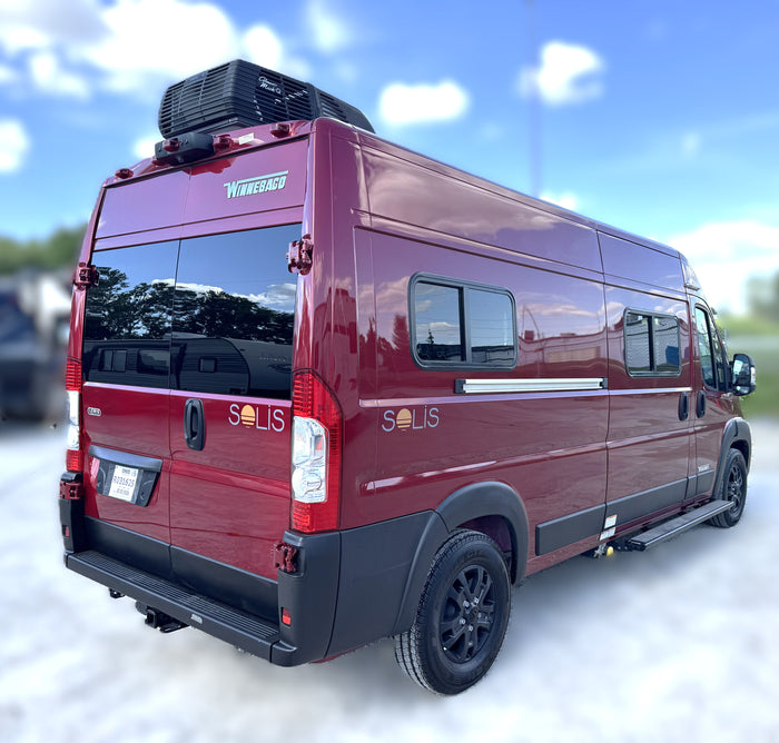 Maroon Winnebago Solis RV rental parked outdoors under a blue sky, featuring a roof-mounted AC unit.