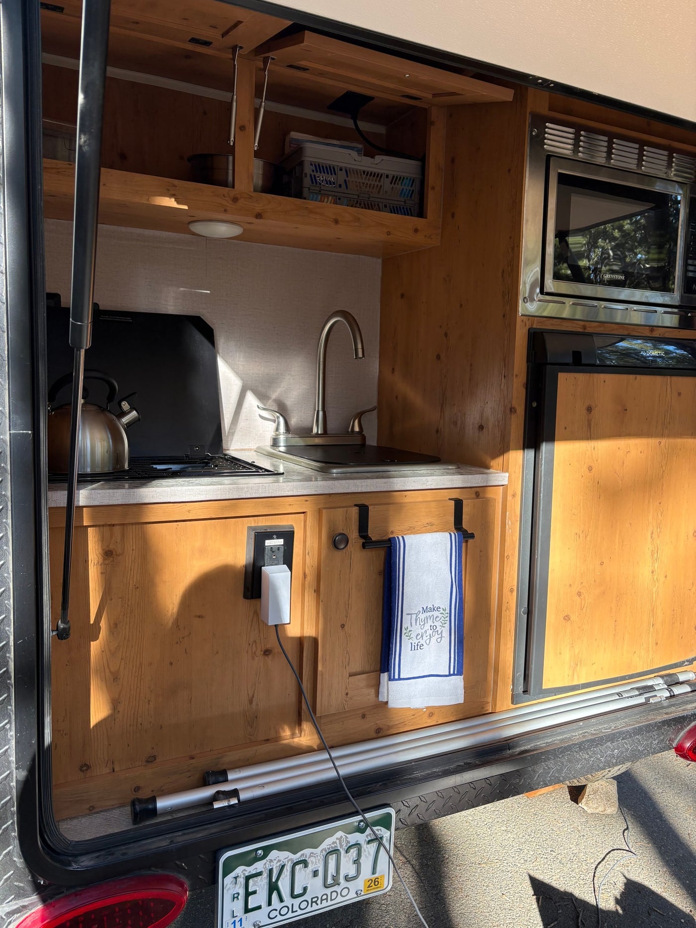This functional rv rental kitchen features a sink, stovetop, microwave, and fridge, all within a compact, wooden setup. — photo 16