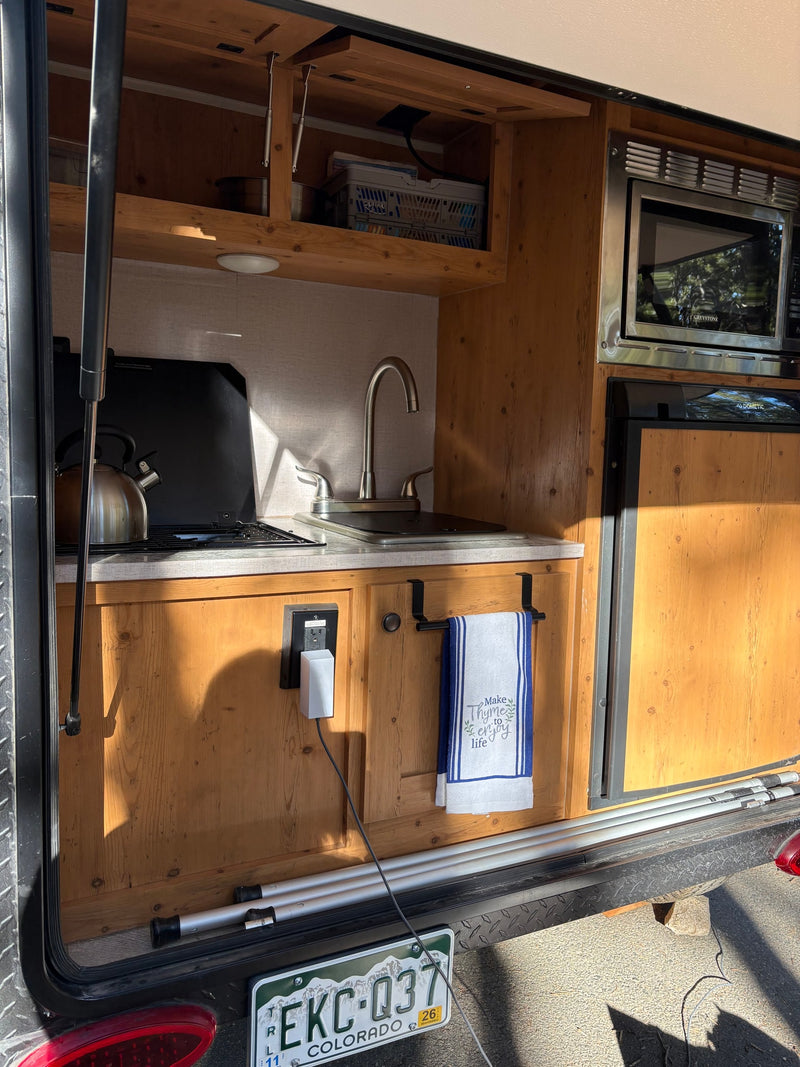 This functional rv rental kitchen features a sink, stovetop, microwave, and fridge, all within a compact, wooden setup. — photo 16
