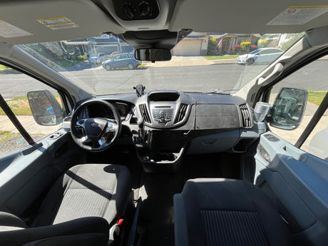 RV rental van interior: Driver's cockpit with Ford steering wheel, dashboard, and outside street view through the windshield.