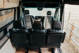 View inside an RV rental showing black passenger seats, dashboard, and outdoor scenery through windows.