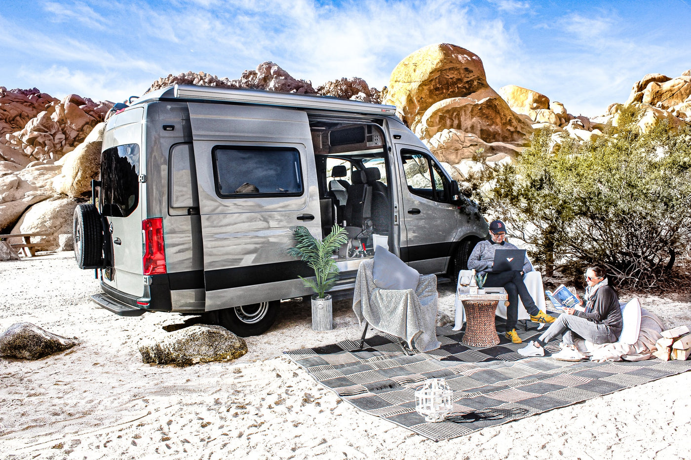 Relax and work remotely in nature with an **rv rental**! Two people enjoy a modern camper van setup in a desert landscape. — photo 2