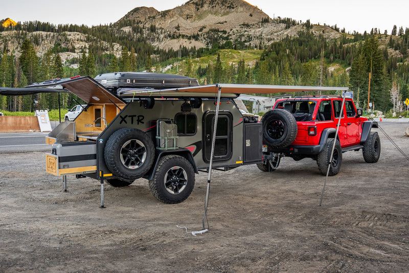 This rv rental setup features a red Jeep and a grey overlanding trailer with an extended awning and kitchen, ready for mountain camping. — photo 3