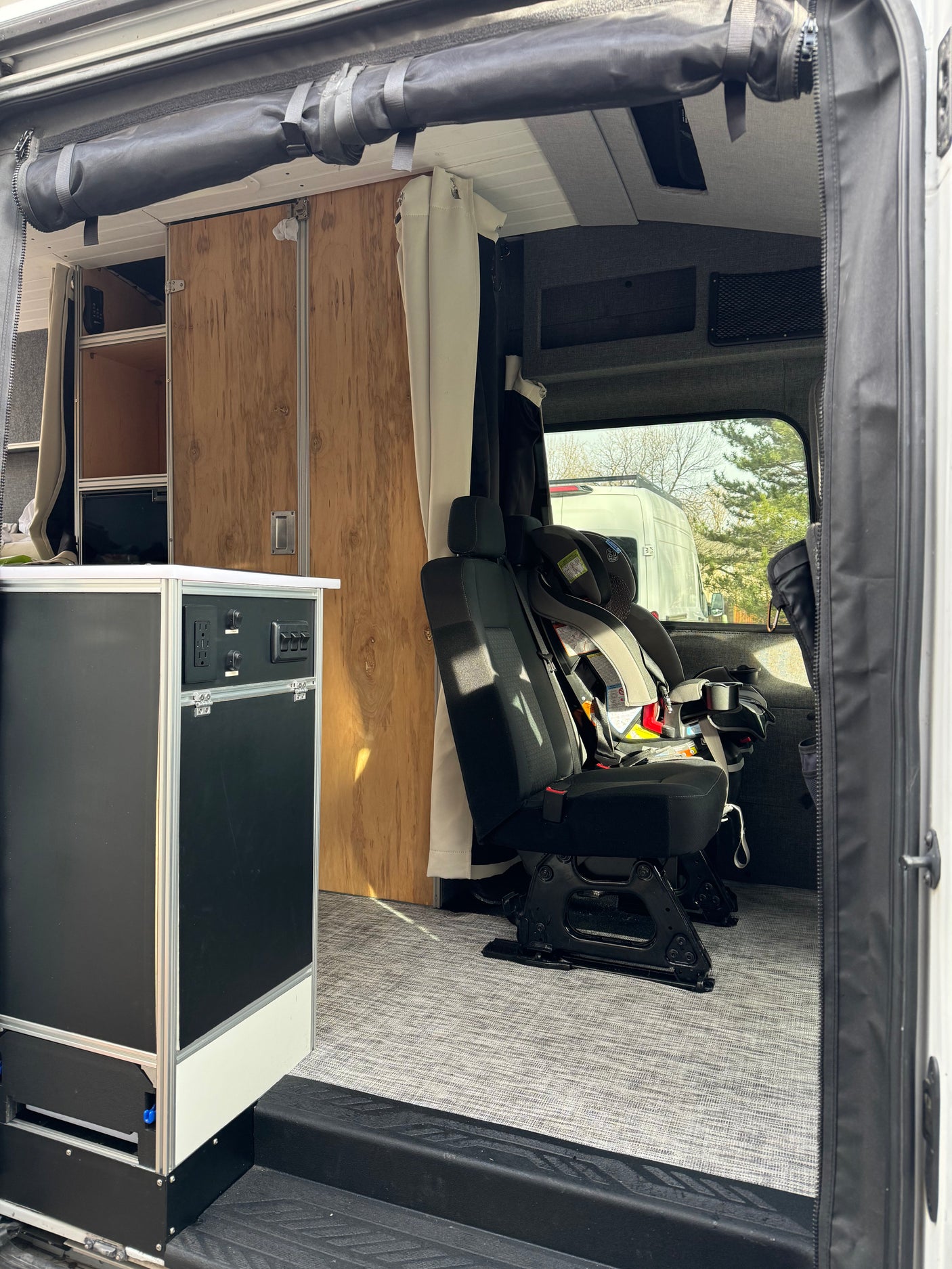 Spacious rv rental interior featuring a child car seat, custom cabinetry, and convenient power outlets.