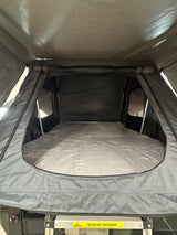 Inside a cozy **RV rental**'s rooftop tent, showing the comfy mattress & sleeping area. Perfect for **camping adventures**.