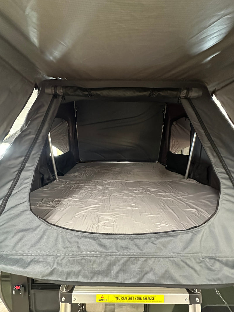  and electric fireplace. Open door shows a backyard fence view.|This dark green Modbug teardrop RV rental features an open door revealing a cozy bed — photo 11