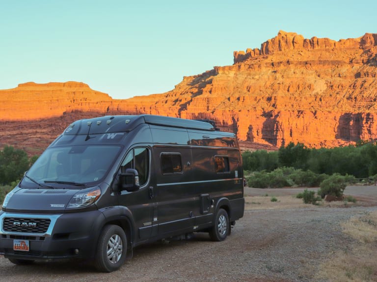 Dark gray camper van RV rental parked on a desert road