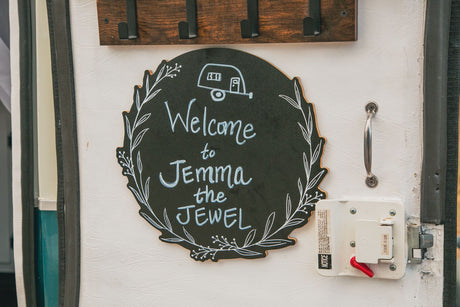 Personalized welcome sign 'Jemma the Jewel' on an RV rental door, with a lock and handle visible.