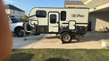 A compact, modern Flagstaff E-Pro travel trailer, ideal for rv rental, parked on a sunny residential driveway near a white truck.