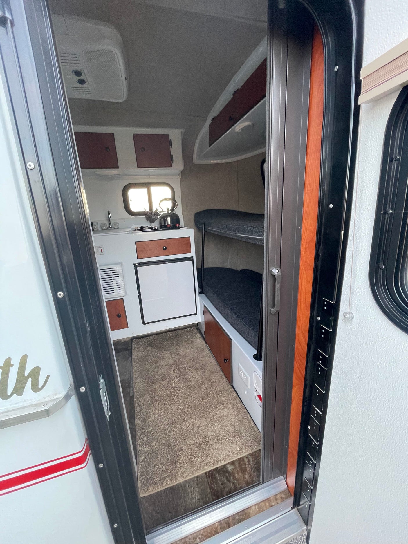Cozy rv rental interior with kitchen, bunk beds, and an AC unit visible. Ideal for compact travel adventures.