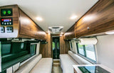 Spacious RV rental interior shows living area with convertible beds, kitchenette, and ample overhead storage cabinets.