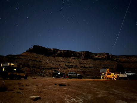 Starry desert night: Jeeps, truck w/ camper, & trailer w/ tent at an overland camp. Experience this adventure with an RV rental!