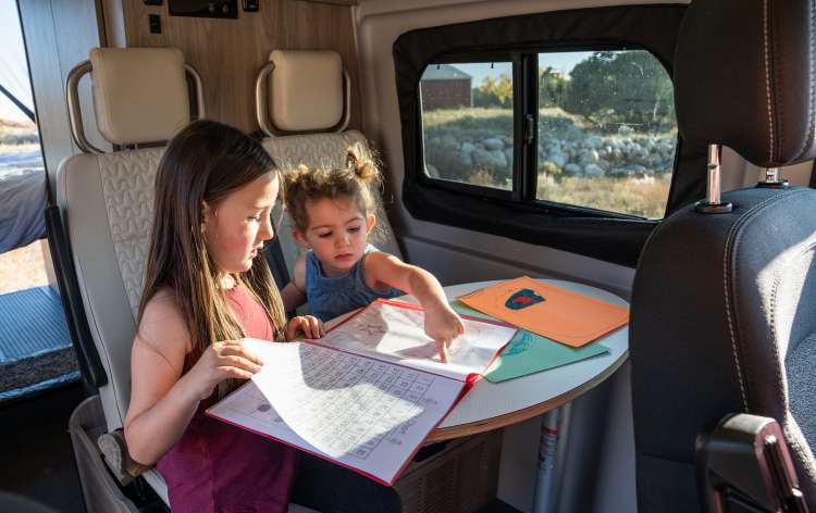  and mesh screen.|Couple enjoys their RV rental camper van bed amidst nature. Perfect for outdoor adventure & travel.|RV rental interior: Man relaxing with drink — photo 10