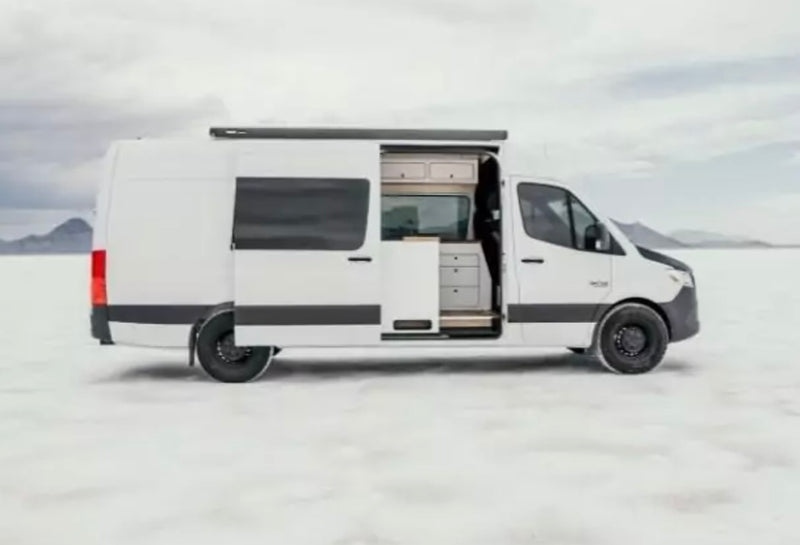 A white RV rental camper van on a vast white landscape with distant mountains. Its side door is open — photo 1