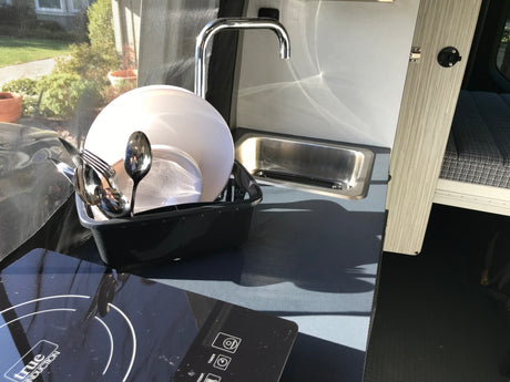 Enjoy an RV rental's functional mobile kitchen with induction cooktop, sink, and dish drying rack for convenient camping.
