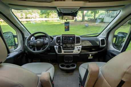 Ready for your RV rental adventure? Interior view of a comfortable camper van's front cabin and open outdoor scene.
