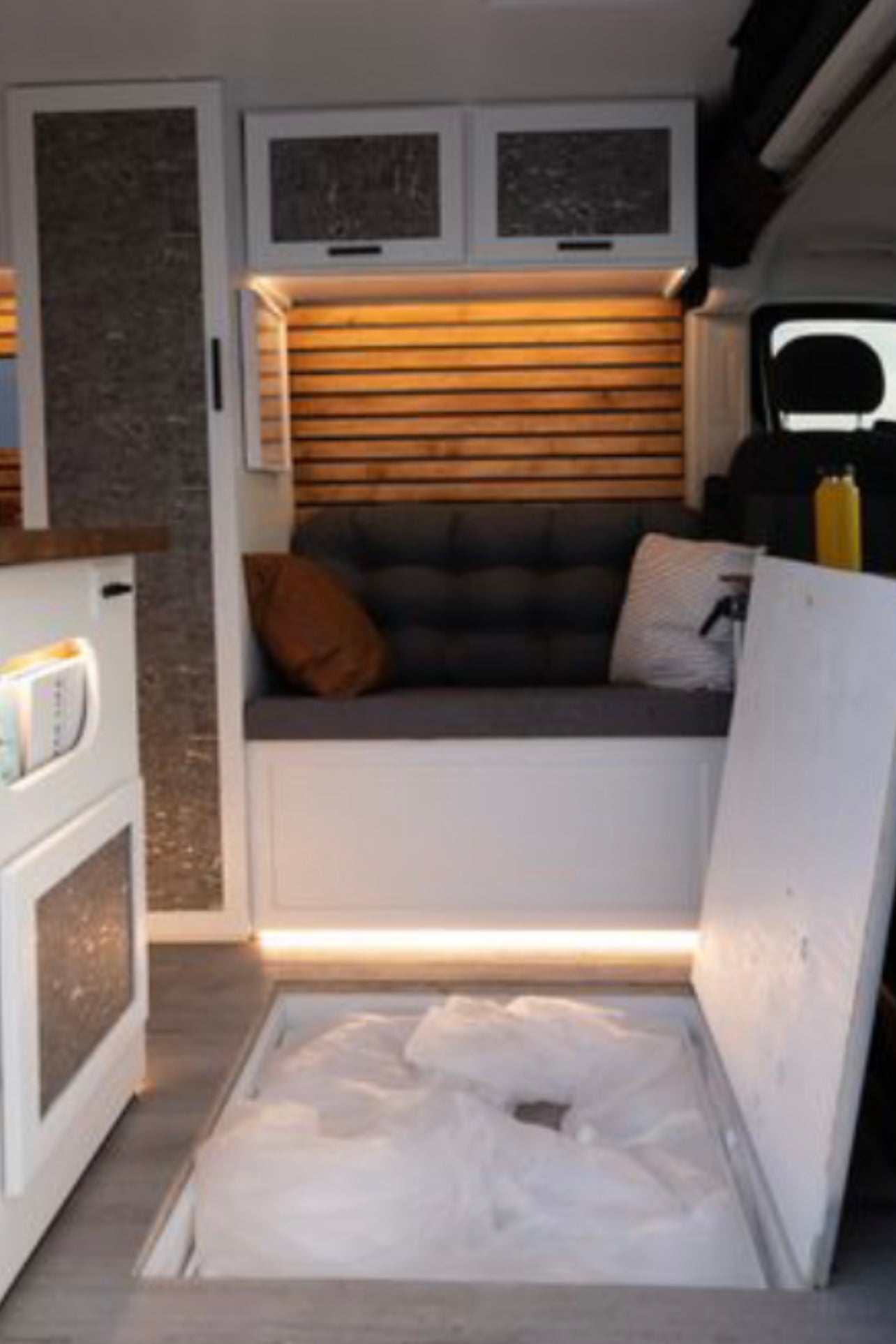 Step inside this RV rental's inviting interior with a cozy bench, wooden accent wall, and unique floor storage.