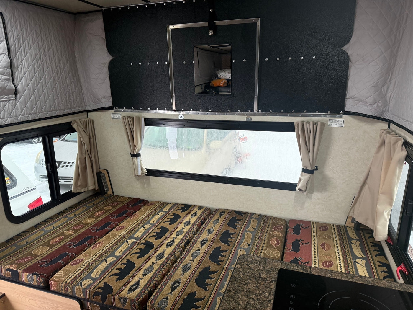 Inside an RV rental: nature-patterned cushions, pop-top walls, and a window for scenic camping views. — photo 13