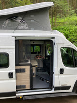 White pop-top camper van, side door open to interior with wine setup. Great for your next rv rental adventure.