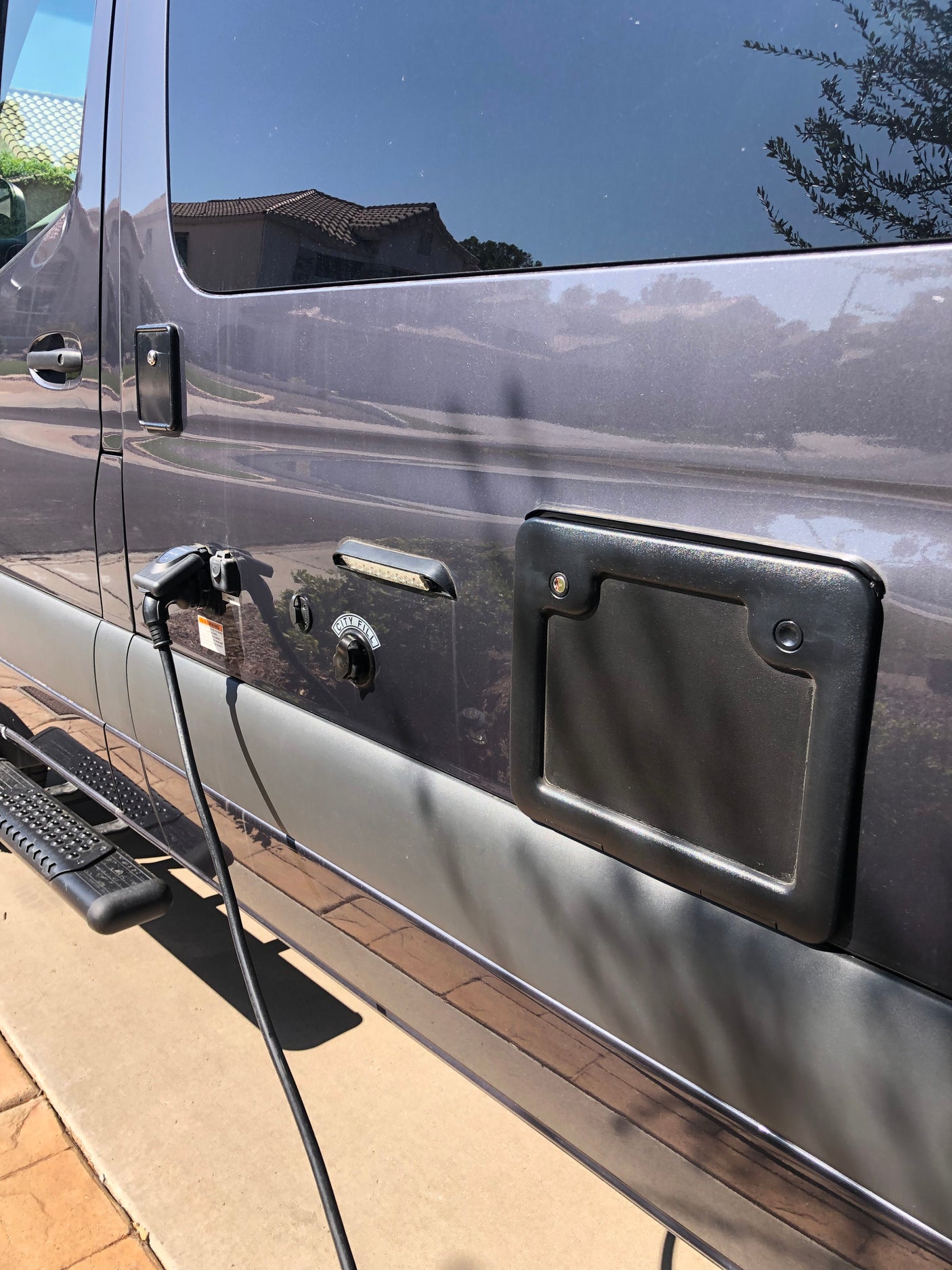 RV rental plugged in for shore power and city water fill. A side step is visible for access.