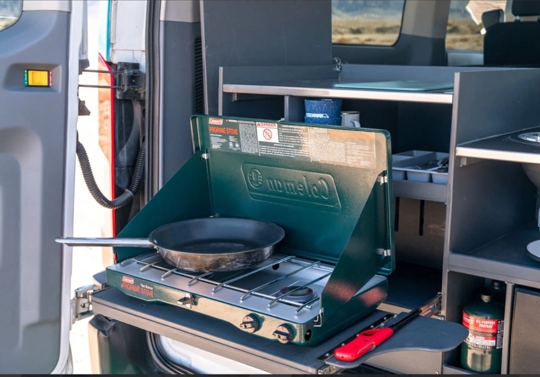  with a scenic lake and desert view outside.|This RV rental camper van features a compact — photo 8