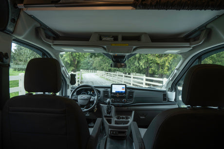 Step into this RV rental! Interior view of the driver's cockpit, steering wheel, and dashboard, ready for a scenic road trip.