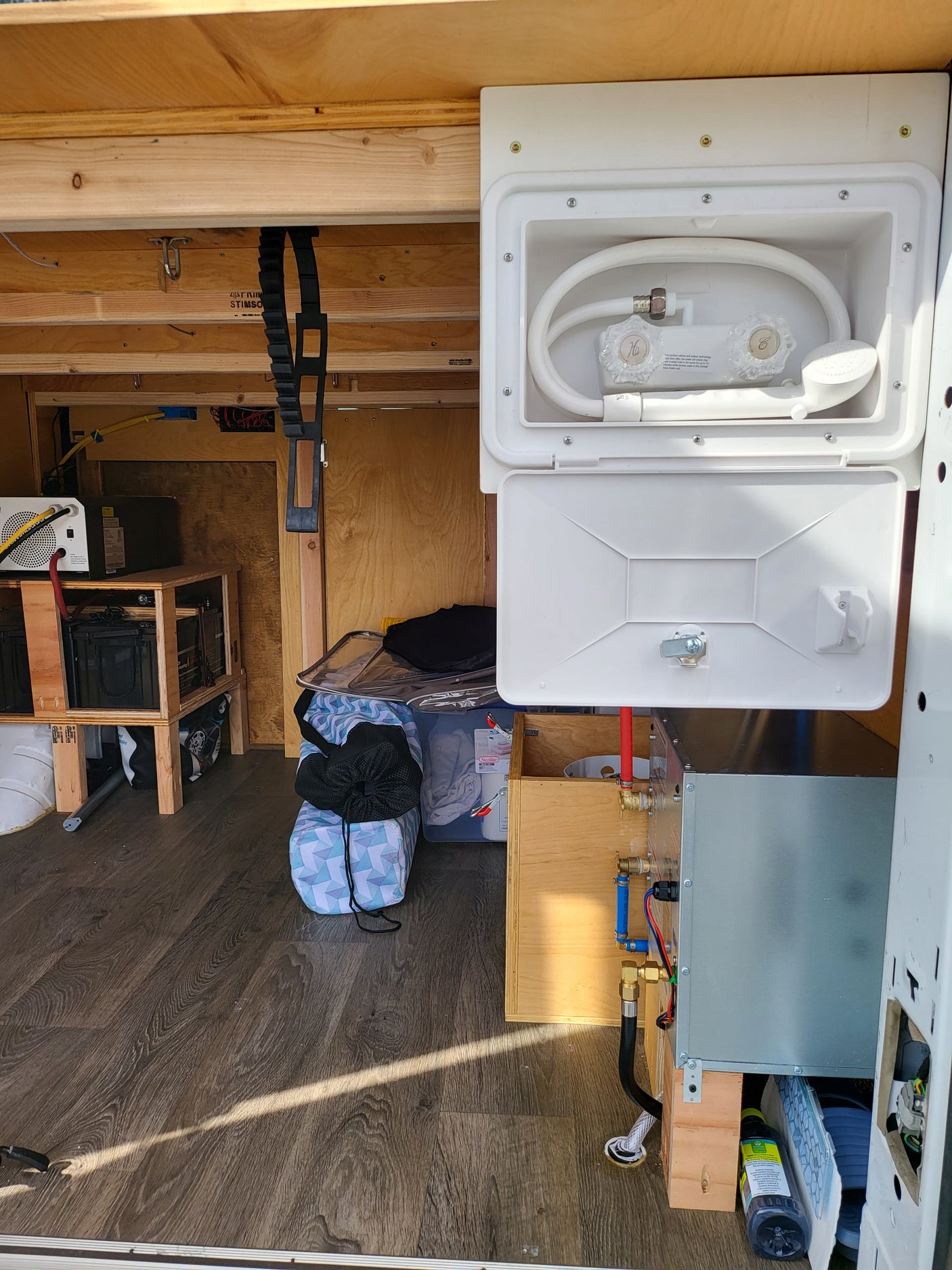 RV rental interior features a custom van build with exterior shower, water heater, and a visible electrical system.