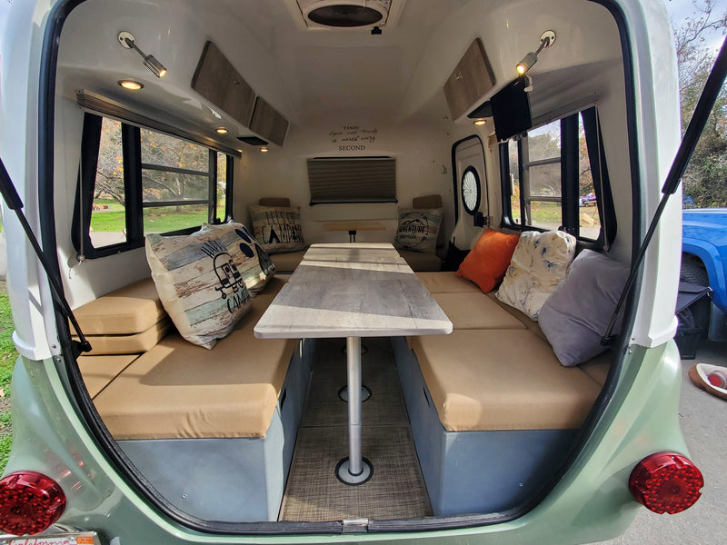 Cozy RV rental interior featuring a bright dinette area with tan cushions and scenic window views, perfect for family travel. — photo 19