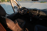 Interior view of an RV rental van. Shows the driver's seat, steering wheel with Ram logo, and dashboard controls.