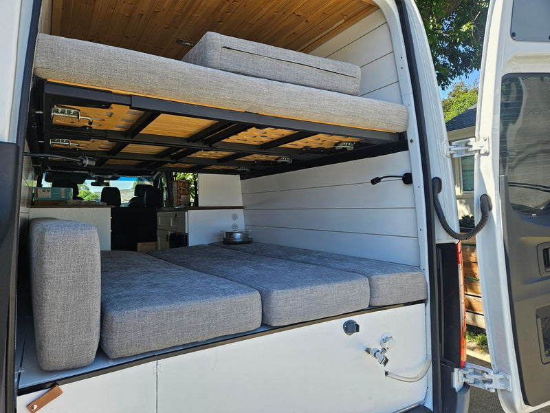 Spacious rv rental interior featuring a bunk bed setup, comfortable gray cushions, and white paneling, ideal for mobile living. — photo 10